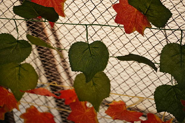 Artificial green and orange leaves are decoratively arranged on a white net structure.