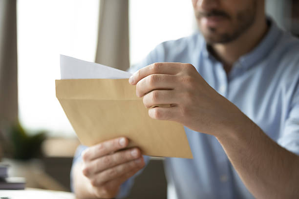 istock Closeup paper letter in postal envelop in young male hands 2255127120