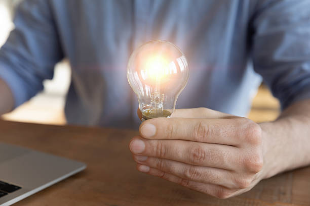istock Closeup businessman working on notebook holding bright light bulb 2255127162