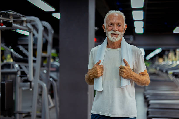 Portrait of positive funky granddad arms hold lift dumbbells wellbeing isolated on yellow color background.