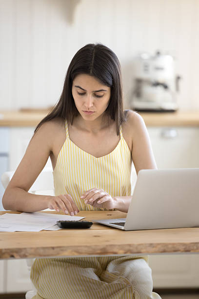 istock Focused woman checks paper document use laptop and calculator 2255129628