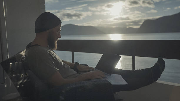 istock Remote Worker Using Laptop on Balcony with Sea View at Sunset 2255130115