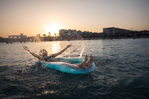 Attractive young woman is wearing swimsuit floating on swimming float, enjoying sunny summer day at the Red Sea, relaxing while on summer vacation.