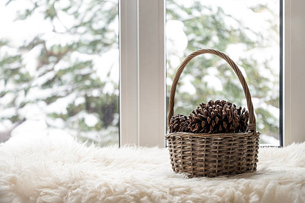 istock Wicker basket with pine cones on cozy winter windowsill 2255132828