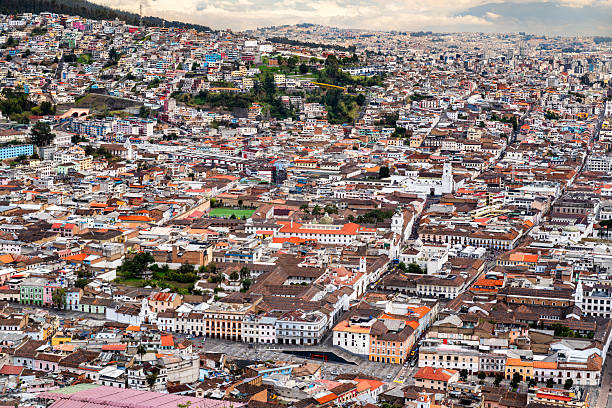 Historic center of Quito spreads out below El Panecillo hill in Ecuador. Panoramic cityscape features colonial churches and red tile roofs in UNESCO World Heritage site