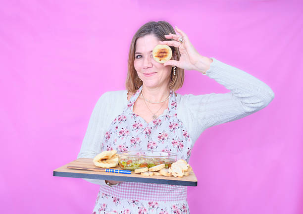 Smiling woman wearing apron holding a board with bread and dip