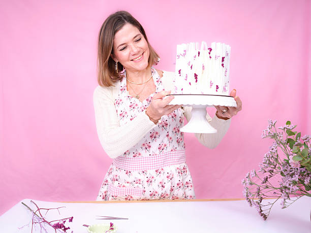 Woman holding decorated floral cake on pink background