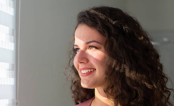 istock Smiling woman looking through window on a sunny day 2255138722