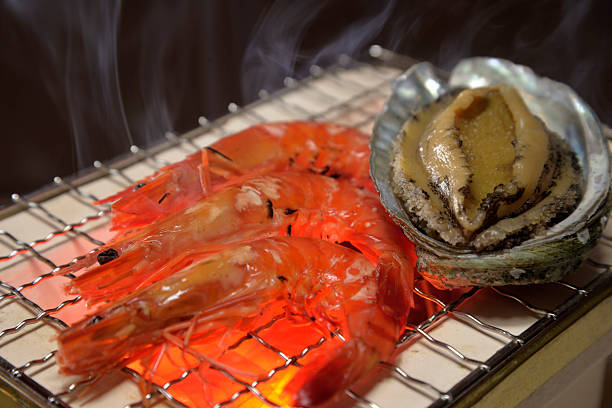 Grilling abalone and shrimp on a smoky charcoal grill