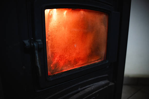 Close-up of intense flames and wood burning inside dark iron stove with visible inner firebox.
