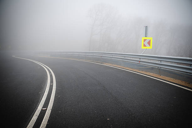 Cars pasing a traffic sign for deer crossing in fog