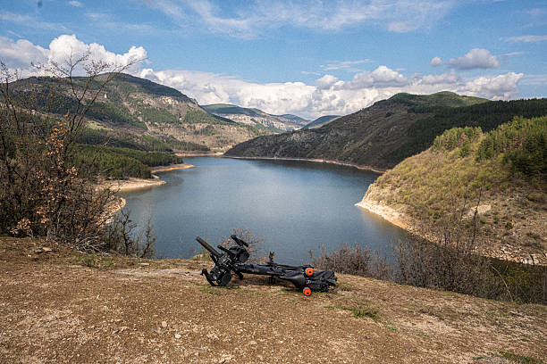 Eco-friendly trip with bicycle in nature. Mature cyclist explores rocky river coast off-season. Sustainable transport, deep rest travel and adventure cycling.