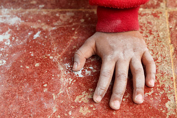 Close-up of a female climber applying chalk to her hands before a bouldering session in a colorful indoor climbing gym. The image highlights preparation and focus in climbing routines.