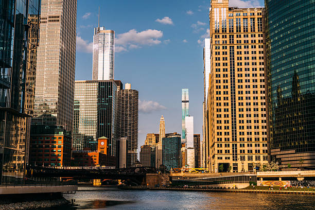 Vertical view of the Chicago River lined with modern skyscrapers and boats sailing through the water on a sunny day in Illinois, USA.