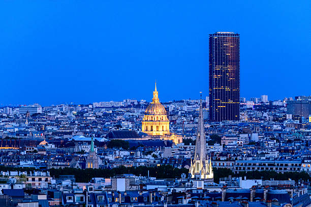 Night view of Pont Alexandre III and Les Invalides in Paris, France, with illuminated statues and street lights.