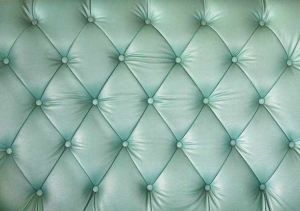 Close-up of a luxury mint green tufted leather texture, showing elegant diamond patterns and button details for classic interior design.