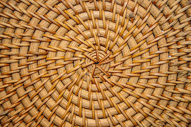 Close-up of a beautifully woven natural rattan texture, forming a circular pattern with intricate details. Perfect for rustic backgrounds