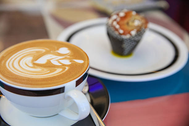 A beautifully crafted artisan latte served in a stylish ceramic cup, featuring smooth creamy microfoam and elegant latte art, captured in a warm and inviting café atmosphere with natural light and wooden textures enhancing the cozy coffeehouse mood.