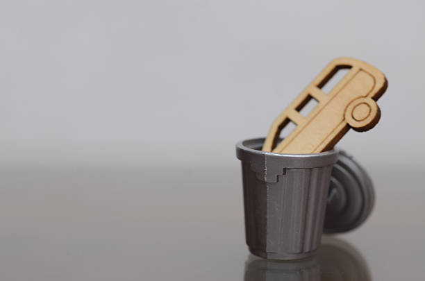 Conceptual image of car waste and environmental responsibility using miniature bin and toy vehicle.