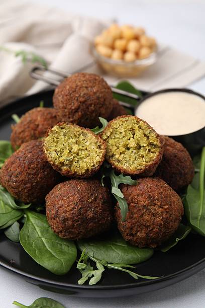 Delicious falafel balls, herbs and sauce on table