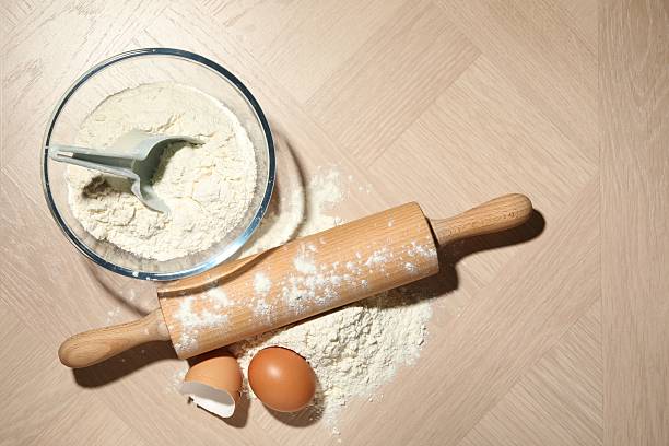 Rolling pin, flour and egg on wooden table, flat lay. Space for text