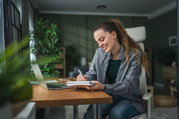istock Young woman smiling writing in notebook during home office 2255182721