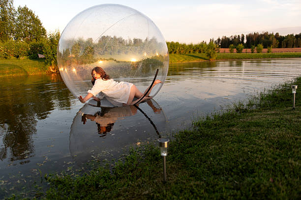 Water ball (similar to zorb or Human Hamster Ball) with young woman inside on pond surface