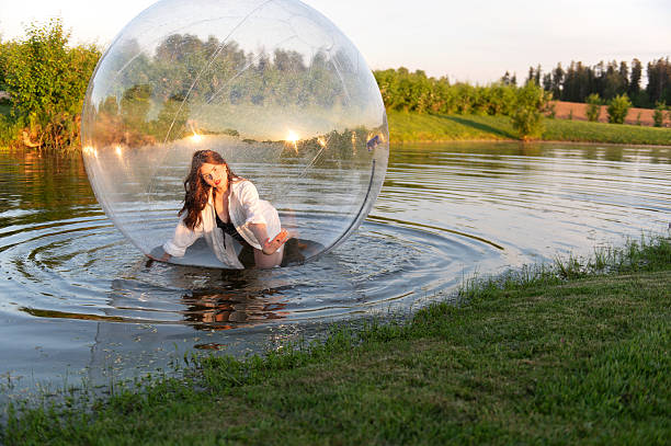istock Water ball (similar to zorb or Human Hamster Ball) with young woman inside on pond surface 2255183837