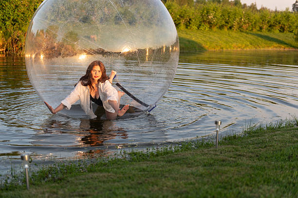 istock Water ball (similar to zorb or Human Hamster Ball) with young woman inside on pond surface 2255183844