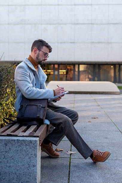 istock Young man writing notes on clipboard outdoor in city 2255184091