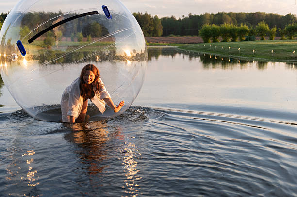 istock Water ball (similar to zorb or Human Hamster Ball) with young woman inside on pond surface 2255184534