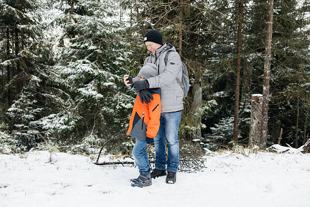 Father and son sharing a moment taking a selfie in a winter forest