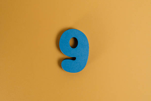 Extruded white number 9 sitting over yellow and blue background. Horizontal composition with copy space.