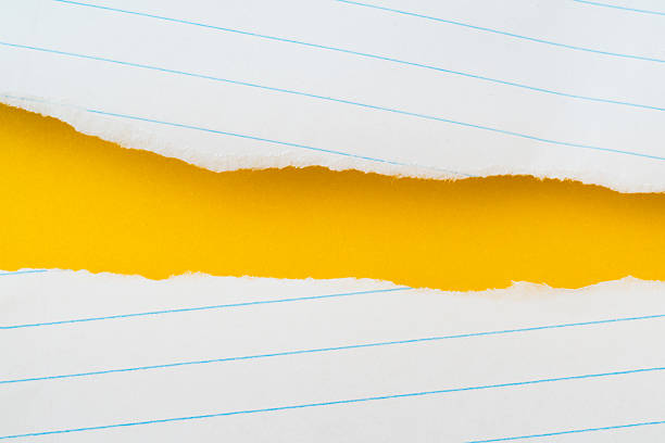 uneven torn white lined paper on grunge yellow paper, top view