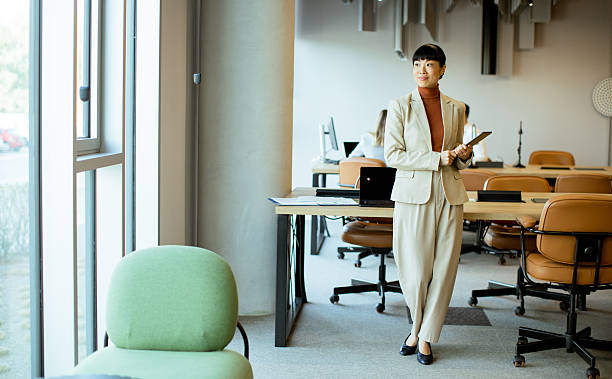 istock Professional woman standing with a notepad in a modern office space during daytime 2255189383