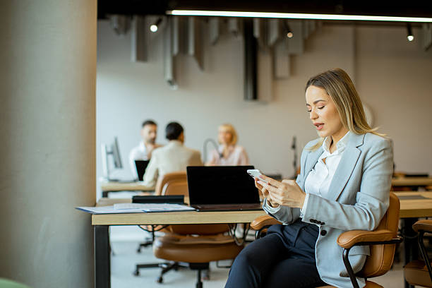 istock Professional woman checking phone in modern office during work hours 2255190441