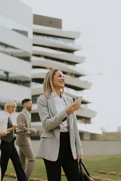 istock Business professionals walking outside a modern building while using their phones 2255190761