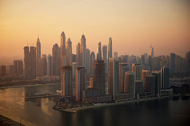 Dubai Marina cityscape at golden hour with numerous towering buildings and water.