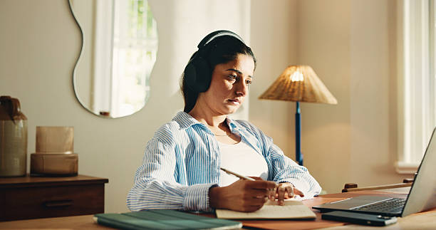 istock Remote work from home, writing and woman with laptop, headphones and notes for creative project. Apartment, freelancer and person with computer, notebook or listening to music, radio and website info 2255193636