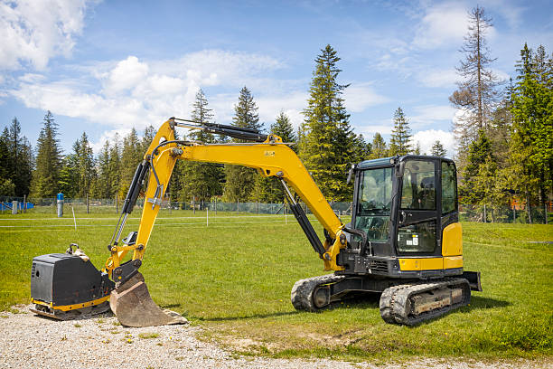 Yellow small excavator with portable compactor in place of future highway, Lesser Poland Voivodenship, Poland