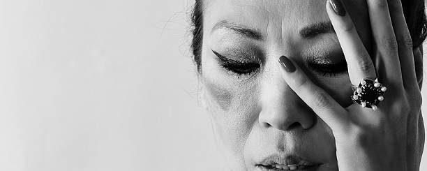 Black-and-white close-up portrait of an Asian woman, with closed eyes and an instinctive hand gesture revealing emotional pain, disappointment, and vulnerability.