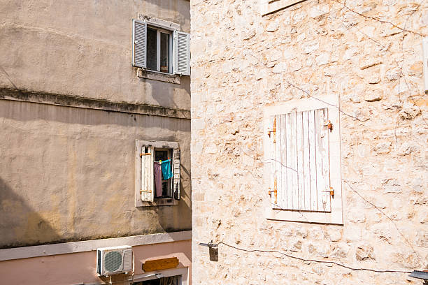 Stone wall with open shutters and laundry. Urban routine, architectural texture, and southern European atmosphere