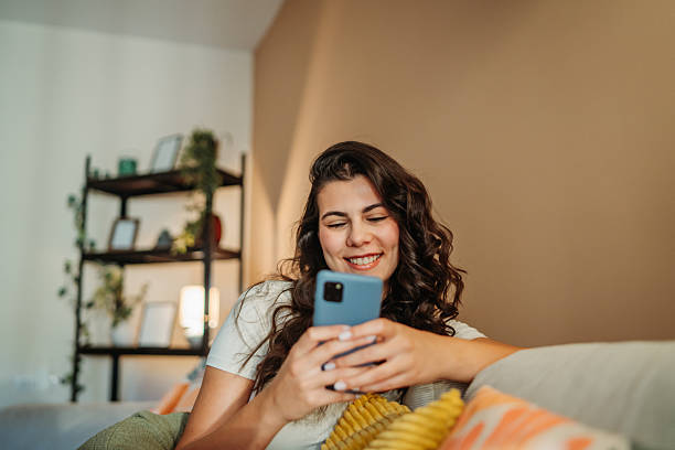 istock Young woman relaxing on couch using smartphone 2255210577