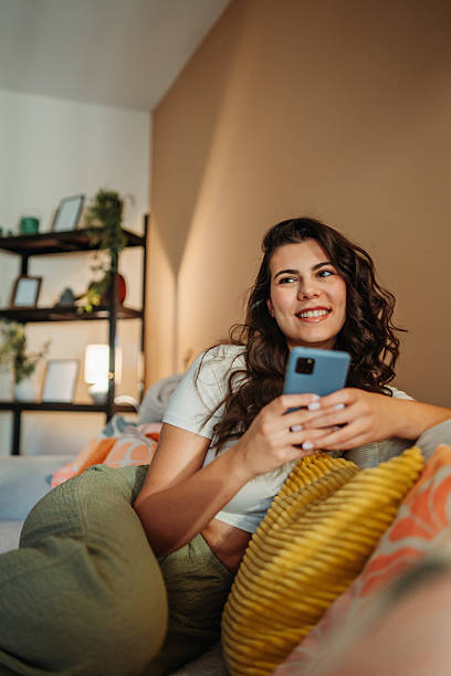 istock Young woman relaxing on sofa using mobile phone 2255210583