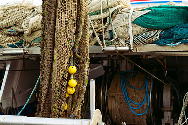 Close-up of fishing nets and ropes with yellow floats stacked on the deck of a traditional fishing boat, showing textures and equipment used in commercial fishing.