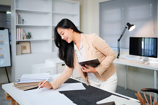 istock Woman reviewing document standing at modern office desk 2255218186