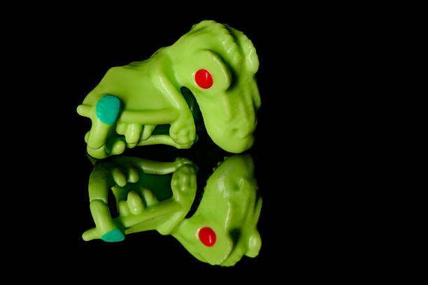 A child is making a clay model of a frog. The frog is green and has a black eye