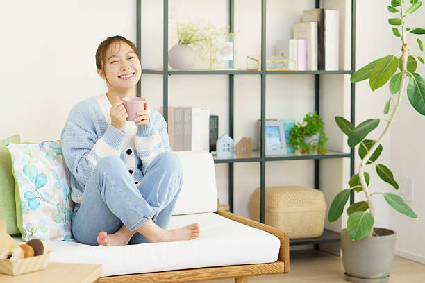 istock Woman sitting on sofa and drinking a drink 2255220538