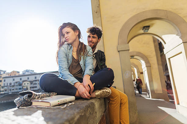 Smiling couple relaxing in grass outdoors and enjoying the day. Man is looking at the camera.