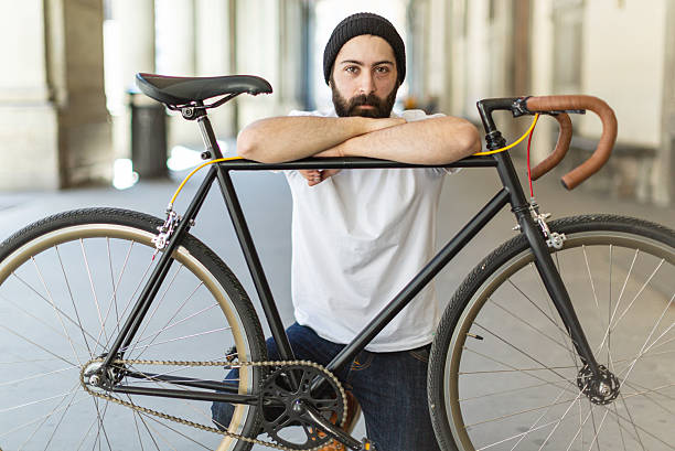 Portrait of a bearded man leaning on his bicycle inside an urban colonnade, combining modern lifestyle, cycling culture, and minimalist city architecture.